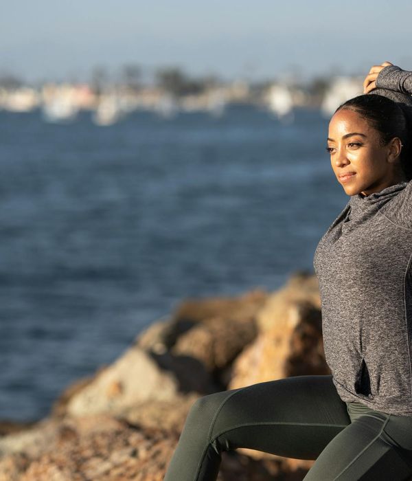 Person stretching energetically outdoors during sunrise.